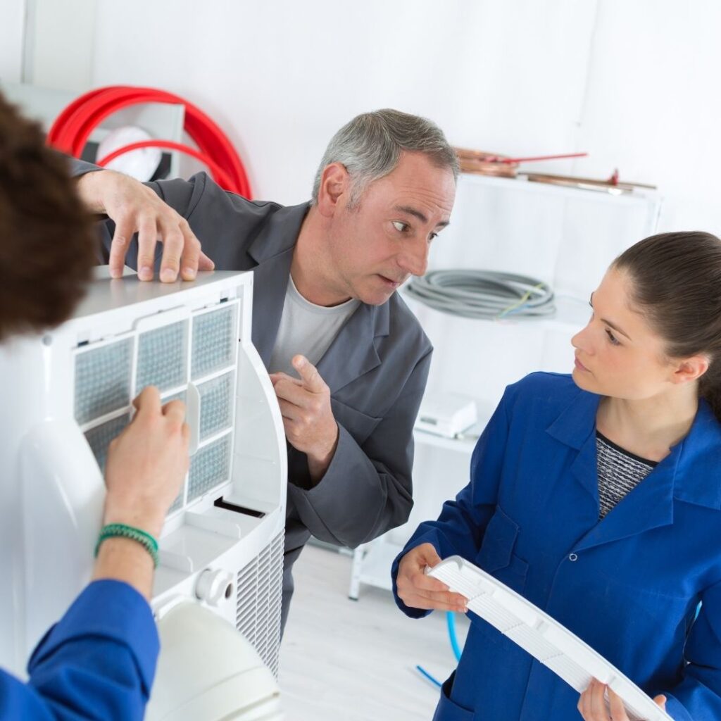 HVAC technicians inspect and demonstrate the air filter component of an indoor cooling system.
